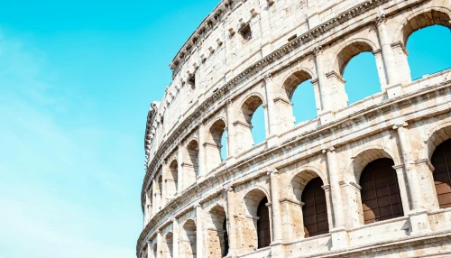 Close-up of the iconic Colosseum in Rome, bathed in sunlight and set against a vibrant blue sky