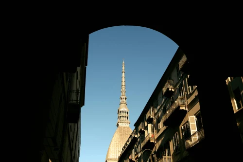 View of Mole Antonelliana under a blue sky, framed by an archway in Turin, Italy