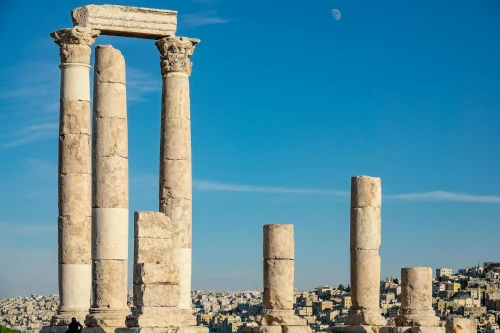 Explore ancient Roman ruins with iconic columns against a clear blue sky in this historic architectural scene