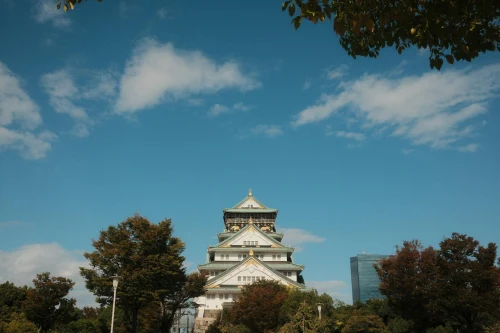 Capture of the iconic Osaka Castle surrounded by trees and a clear blue sky in Osaka, Japan