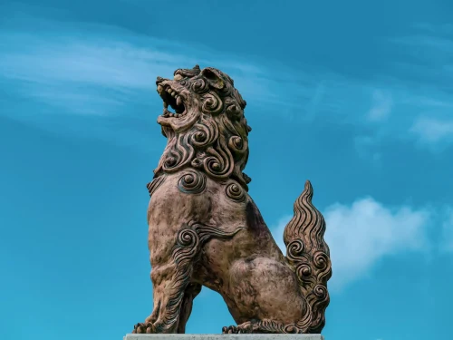 Majestic Shisa statue with intricate design set against a vibrant blue sky, symbolizing protection and cultural heritage