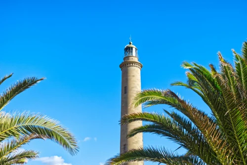 Maspalomas Lighthouse with palm trees and blue sky, a famous landmark in Canarias, Spain