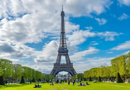 A scenic view of the Eiffel Tower with people enjoying the sunny day in Paris, France