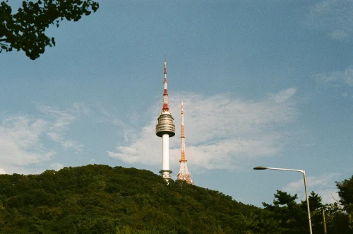 Iconic Namsan Seoul Tower under a clear blue sky captured amid lush greenery