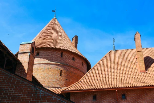 A vibrant image of a historic brick castle with blue sky in Lithuania, showcasing unique architecture