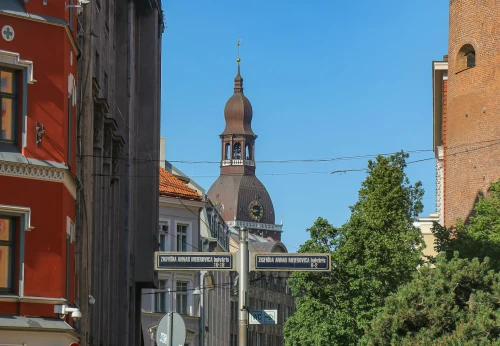 View of Riga Cathedral tower framed by historic buildings and a clear blue sky in Riga, Latvia