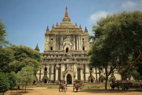Scenic view of the historic Thatbyinnyu Temple with horse carriages under a blue sky in Bagan, Myanmar