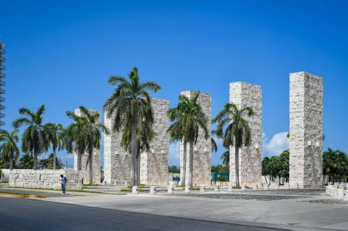 Stone columns and palm trees in a sunny urban setting in Cancún, Mexico