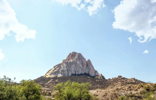 view of Peña de Bernal's rocky peak against a bright blue sky in Mexico