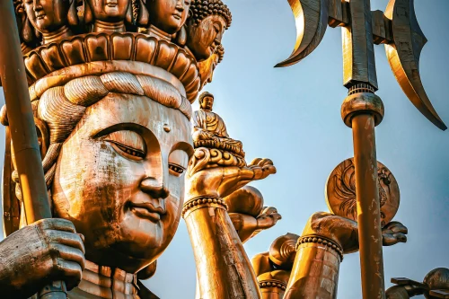 Close-up of a golden Buddha statue with intricate details set against a clear blue sky