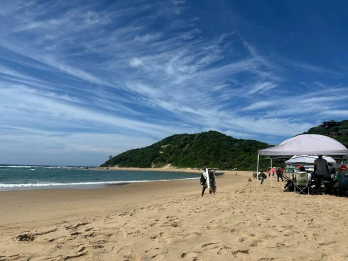 People enjoying a sunny day at the beach in Ponta do Ouro, Mozambique, with clear blue skies and scenic views