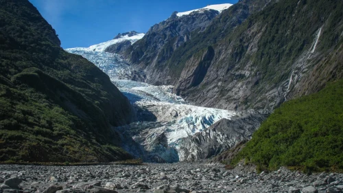 Captivating view of a glacier nestled between rugged mountain valleys under a clear blue sky