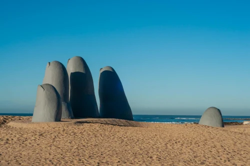 Iconic hand sculpture on sandy beach in Punta del Este, Uruguay with clear blue sky
