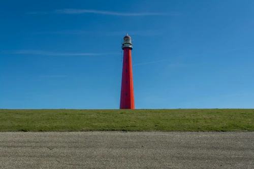 A striking red lighthouse under a blue sky in Den Helder, Netherlands