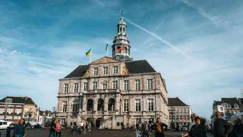 A bustling scene at Maastricht City Hall with people walking under a clear blue sky