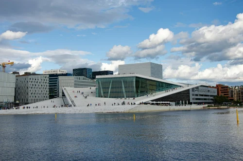 Stunning view of the Oslo Opera House by the waterfront under a blue sky, showcasing modern architecture
