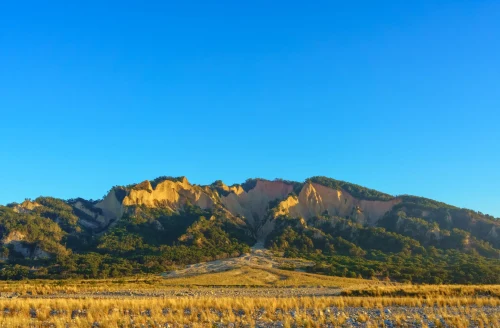 A picturesque mountain range with unique formations under a sunny clear blue sky, perfect for nature lovers