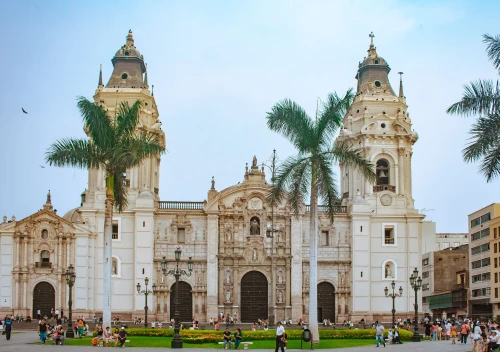 Capture of Lima Cathedral with palm trees and visitors under a blue sky