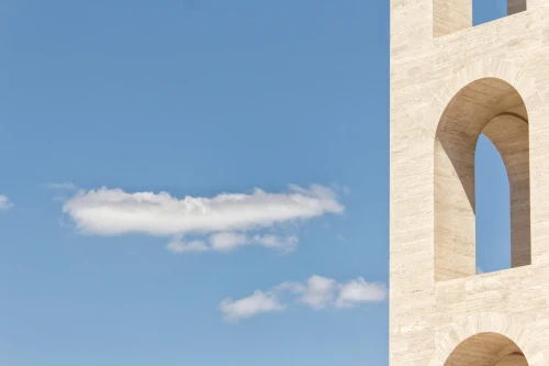 Minimalist view of architectural arches against a blue sky in Rome
