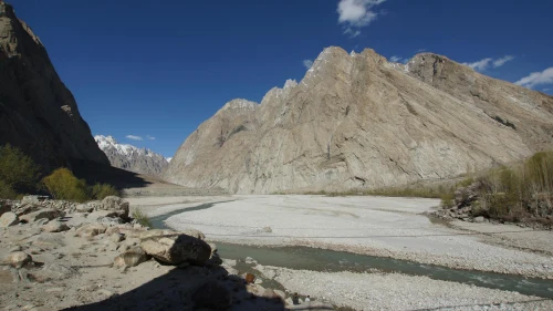 view of a rocky mountain range with a winding river under a clear blue sky