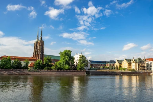 Scenic view of Wrocław Cathedral along the Oder River under a bright blue sky