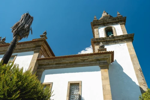 A stunning view of a historic church tower against a clear blue sky in Vila Real, Portugal