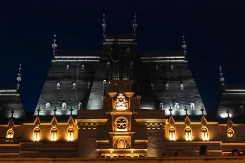 Illuminated facade of the Palace of Culture in Iași, Romania at night, showcasing architectural elegance