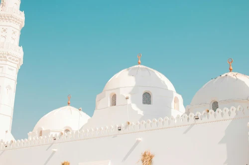 Majestic white domes of a mosque against a clear blue sky in Saudi Arabia