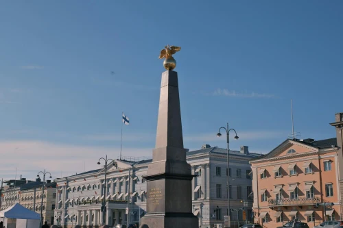Obelisk with golden eagle at Helsinki's Market Square under a clear blue sky