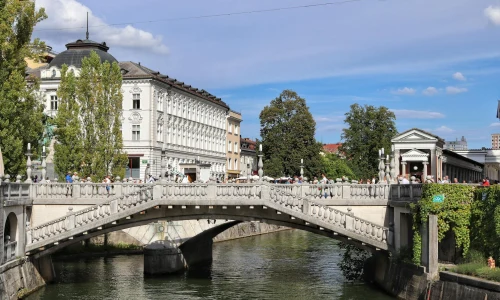 Sunny day at Ljubljana's iconic Triple Bridge with bustling pedestrians