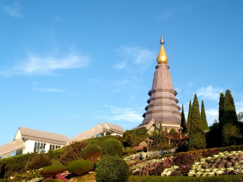 Beautiful view of a Buddhist pagoda surrounded by a vibrant garden in Chiang Mai, Thailand, under a clear blue sky