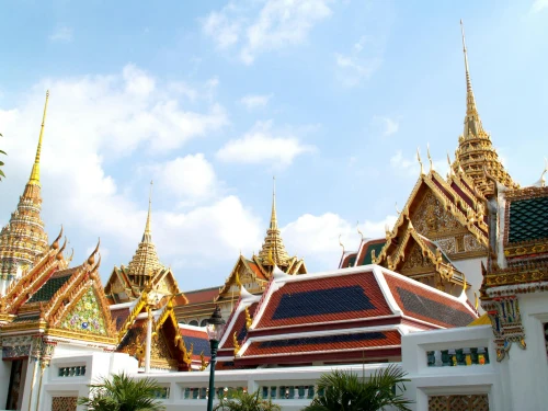 Majestic view of ornate Thai architecture with golden spires under a bright blue sky in Bangkok's Grand Palace