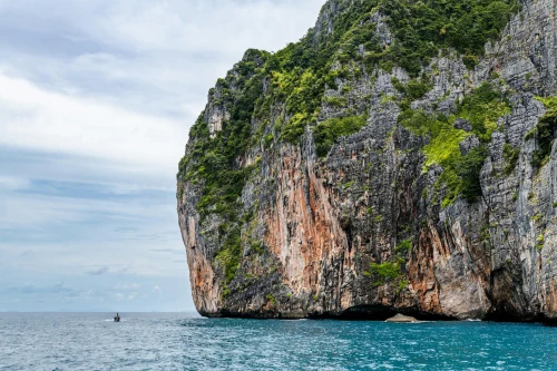 Majestic cliff rising from turquoise sea under a clear sky in Phuket, Thailand