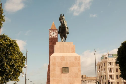 Iconic view of a statue and clock tower under a sunny sky in Tunis, Tunisia