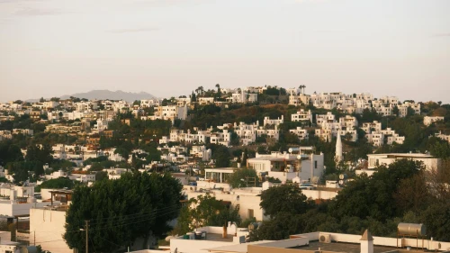 Panoramic view of Bodrum's iconic white buildings on a hillside under a warm sunset glow