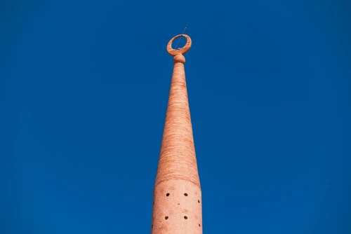 A high minaret stands prominently with a deep blue sky background, symbolizing Islamic architecture