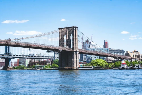 Amazing scenery of famous Brooklyn Bridge over river connecting districts of New York City against blue sky