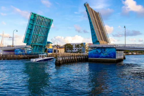A boat sails through a vibrant blue drawbridge on a sunny day, capturing urban waterfront life