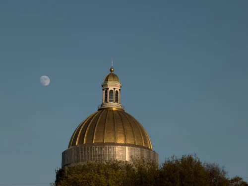 A majestic golden dome with a clear sky and visible moon, showcasing architectural beauty
