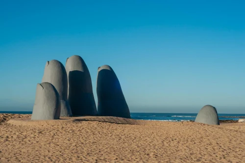 Iconic hand sculpture on sandy beach in Punta del Este, Uruguay with clear blue sky