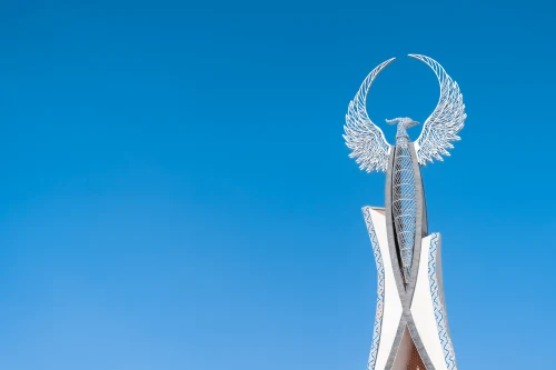 This striking monument with winged design rises against a bright blue sky in Akbarak, Uzbekistan