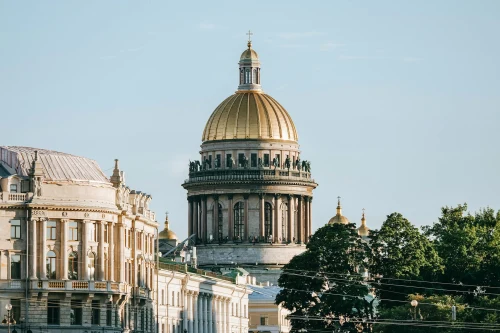 St. Isaac's Cathedral dome under a clear sky with surrounding architecture and trees