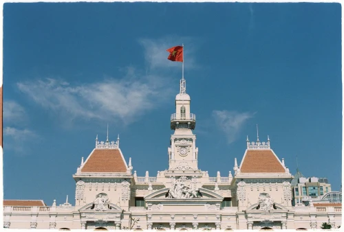 Iconic Ho Chi Minh City landmark with Vietnamese flag against a clear blue sky